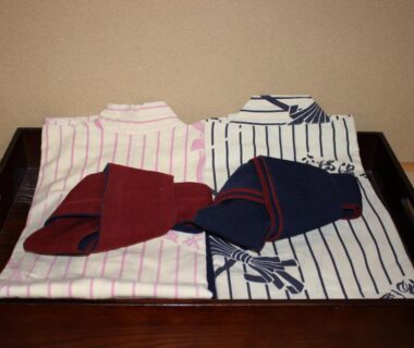 Two folded striped yukata and obi on a wooden tray in a tatami room at Ryokan Tanaka, Gifu