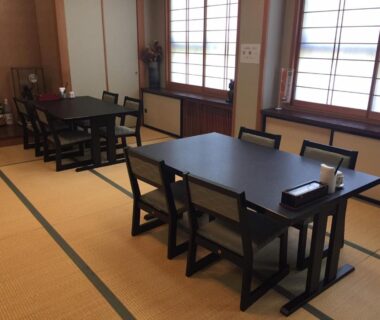 Tatami-floored dining room with low tables, wooden chairs and shoji screens at Ryokan Tanaka in Gifu