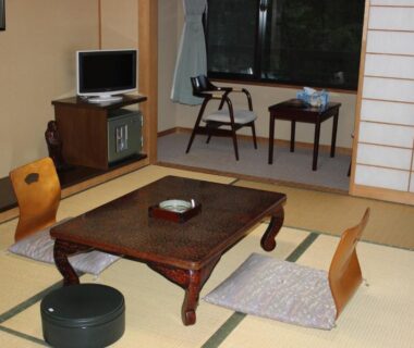 Tatami room with low wooden table, floor cushions and shoji screens at Ryokan Tanaka in Gifu