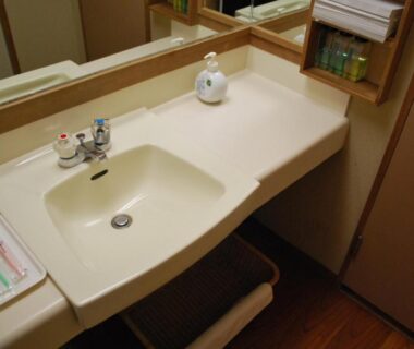 Sink and vanity counter with toiletries, mirror and towels in Ryokan Tanigawa wash area, Gunma