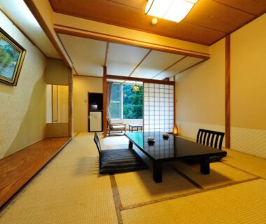 Traditional tatami room with low table, shoji screens and view of greenery at Ryokan Tanigawa, Gunma