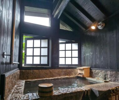 Indoor stone and wooden onsen bath with shoji windows at Ryokan Tenryu in Oita
