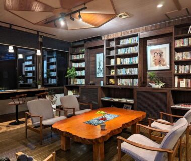 Warm wooden lounge with bookshelves and low table at Ryokan Tenryu in Oita, Kyushu, Japan