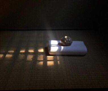 Small metal bell on white cloth on tatami with shoji light at Ryokan Tori Kyoto