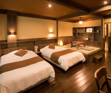 Wooden room with two beds and tatami seating area at Ryokan Wakaba, Kumamoto, Kyūshū, Japan