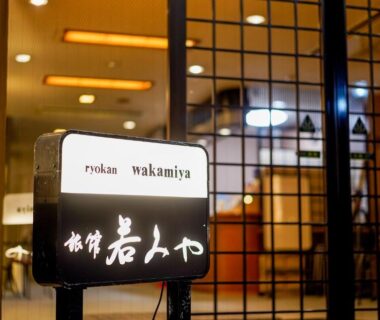 Illuminated entrance sign with shoji screens and warm lobby lighting at Ryokan Wakamiya, Kyoto