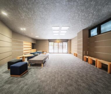 Carpeted lounge with wooden benches and low seating at Ryokan Wakamiya in Kyoto