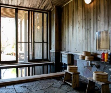Wooden indoor onsen with stone floor and wash stools at Ryokan Warabino, Nagano, Chūbu