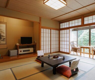 Traditional tatami room with chabudai, zabuton cushions, shoji screens and garden view at Ryokan Warabino in Nagano