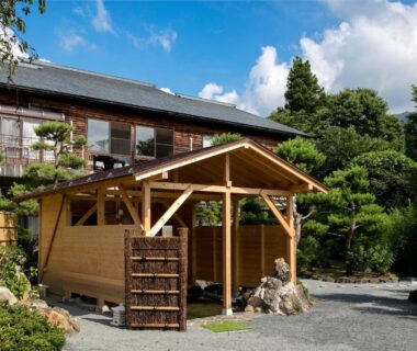 Traditional wooden entrance pavilion with gravel courtyard and landscaped greenery at Ryokan Warabino in Nagano