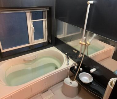 Indoor bathtub with handheld shower, stool and window at Ryokan Yamaichi Hokkaido