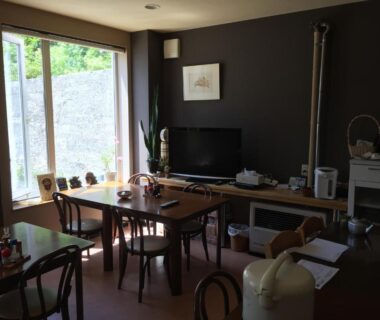 Communal dining room with wooden table, chairs and TV at Ryokan Yamaichi in Hokkaidō, Japan