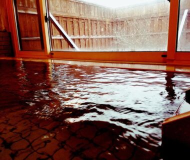 Wood-lined indoor onsen with sliding window and rippling water, Ryokan Yamakanoyu Nagano