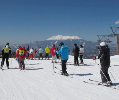 Skiers on snowy slope with distant mountain near Ryokan Yamakanoyu, Nagano, Chūbu, Japan