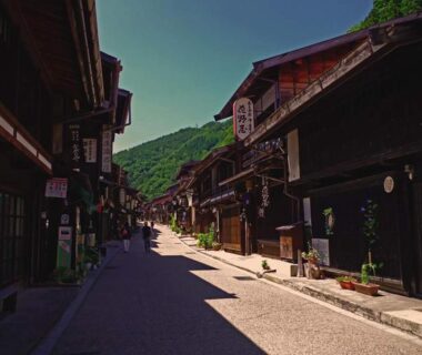 Narrow historic street lined with wooden facades and mountains beyond near Ryokan Yamakanoyu, Nagano