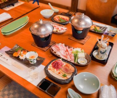 Table with small tabletop hot pots and assorted dishes at Ryokan Yamanoyu, Kumamoto, Kyūshū, Japan