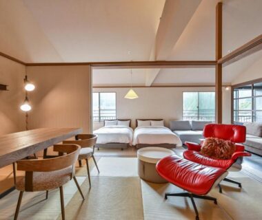 Tatami room with low beds, dining area and red lounge chair at Ryokan Yoshidaya, Saga, Kyūshū