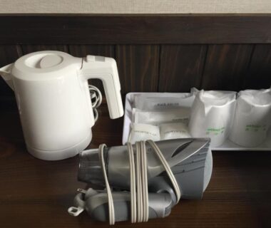 Electric kettle, wrapped cups and corded hair dryer on a wooden ryokan room counter