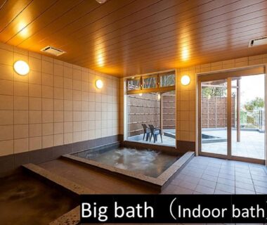 Spacious tiled indoor onsen bath with wooden ceiling and glass doors opening to an outdoor area at Miyajima-an, Hiroshima