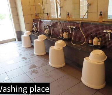 Onsen washing station with stools and handheld showers at Ryokan Miyajima-an Hiroshima