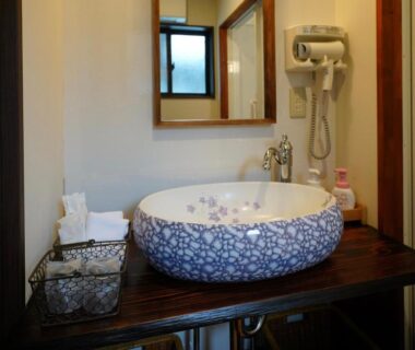 Blue and white ceramic wash basin on wooden counter with mirror and hairdryer at Ryokoji Temple, Kumamoto