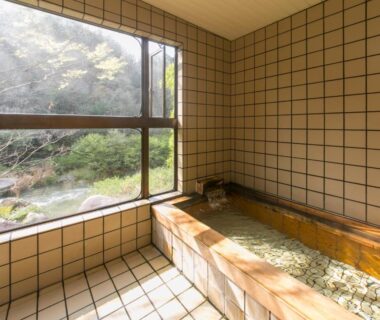 Indoor wooden bath with river view at Ryori Ryokan Shikanoyu Gifu