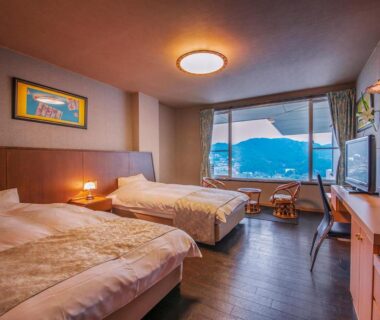 Twin beds, seating area and large window with mountain view at Ryoso Uminocho, Mie