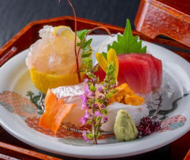 Assorted sashimi with tuna, salmon and sea urchin, garnishes and wasabi on ceramic plate