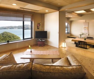 Spacious tatami and sofa seating with low table and large window overlooking coastal views at Ryoso Uminocho Mie