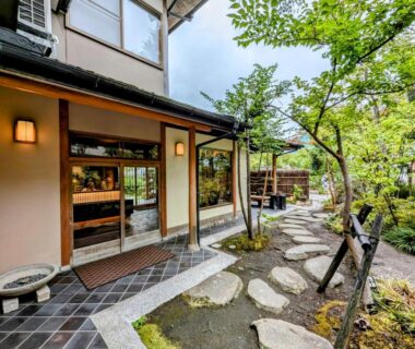 Stone stepping path leading to wooden ryokan entrance with lanterns and lush garden at Ryoso Yufuin Yamadaya, Oita