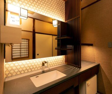 Backlit mirror and sink with wooden counter in traditional Japanese ryokan bathroom at Ryoso Yufuin Yamadaya Ōita