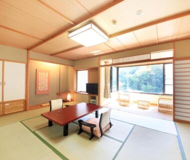 Spacious tatami room with low table, shoji screens and balcony seating overlooking greenery at Ryotei Hanayura, Hokkaidō