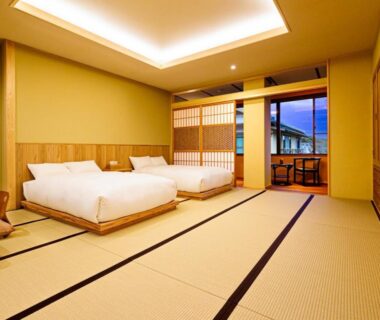 Spacious tatami room with twin Western beds, shoji screens, wooden interior and balcony at Ryotei Jyusouya in Nara