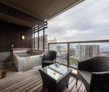 Balcony soaking tub with wicker chairs and city view at Ryotei Matsubaya in Ōita, Kyūshū, Japan