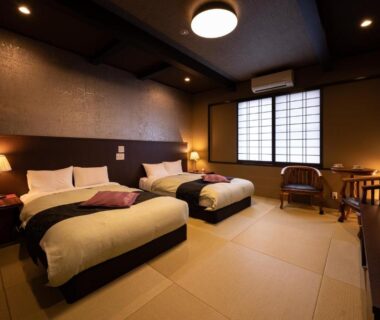 Tatami-floored twin room with shoji screens, low table, chairs and warm ambient lighting at Ryotei Matsubaya, Ōita