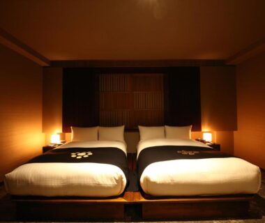 Twin beds in softly lit Japanese-style room with wooden headboard and bedside lamps
