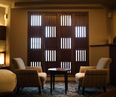 Two upholstered chairs and round table before wooden lattice doors at Ryotei Matsuya Honkan Suizenji in Kumamoto Kyūshū