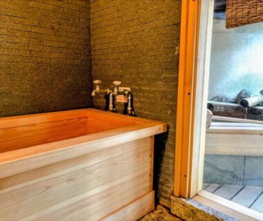 Wooden soaking tub with toiletries beside glass door at Ryotei Tanokura in Oita, Kyushu