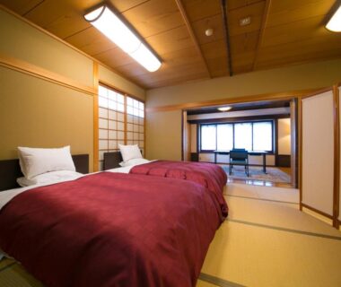 Tatami room with twin beds, shoji screens and seating area at Ryotei Tanokura in Ōita, Kyūshū, Japan