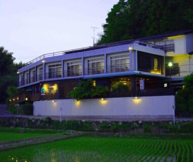 Lit evening facade and balcony overlooking rice paddies at Ryoufuso in Mie, Kansai region