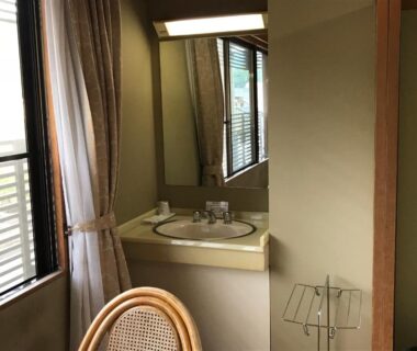 Vanity sink with mirror, wicker chair and window in Ryujin Onsen Marui Ryokan, Wakayama