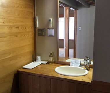 Wooden vanity with sink and mirror opening to tatami room at Ryujin Onsen Marui Ryokan, Wakayama