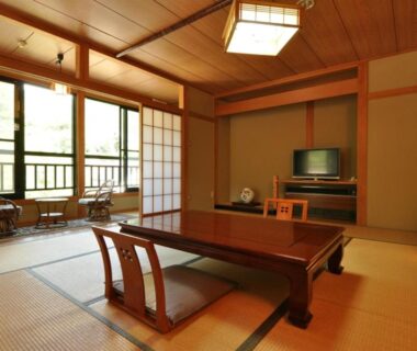 Traditional tatami room with low table, zaisu chairs, shoji screens and balcony overlooking trees at Ryuudo in Gunma