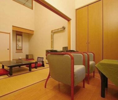 Traditional tatami room with low table, zabuton cushions, armchairs and tokonoma alcove at Ryuudo in Gunma