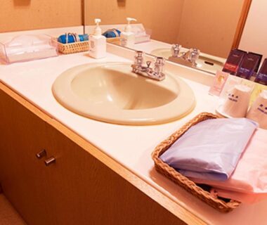 Countertop sink with mirror, toiletries and folded linens at Ryuudo bathroom, Gunma, Japan