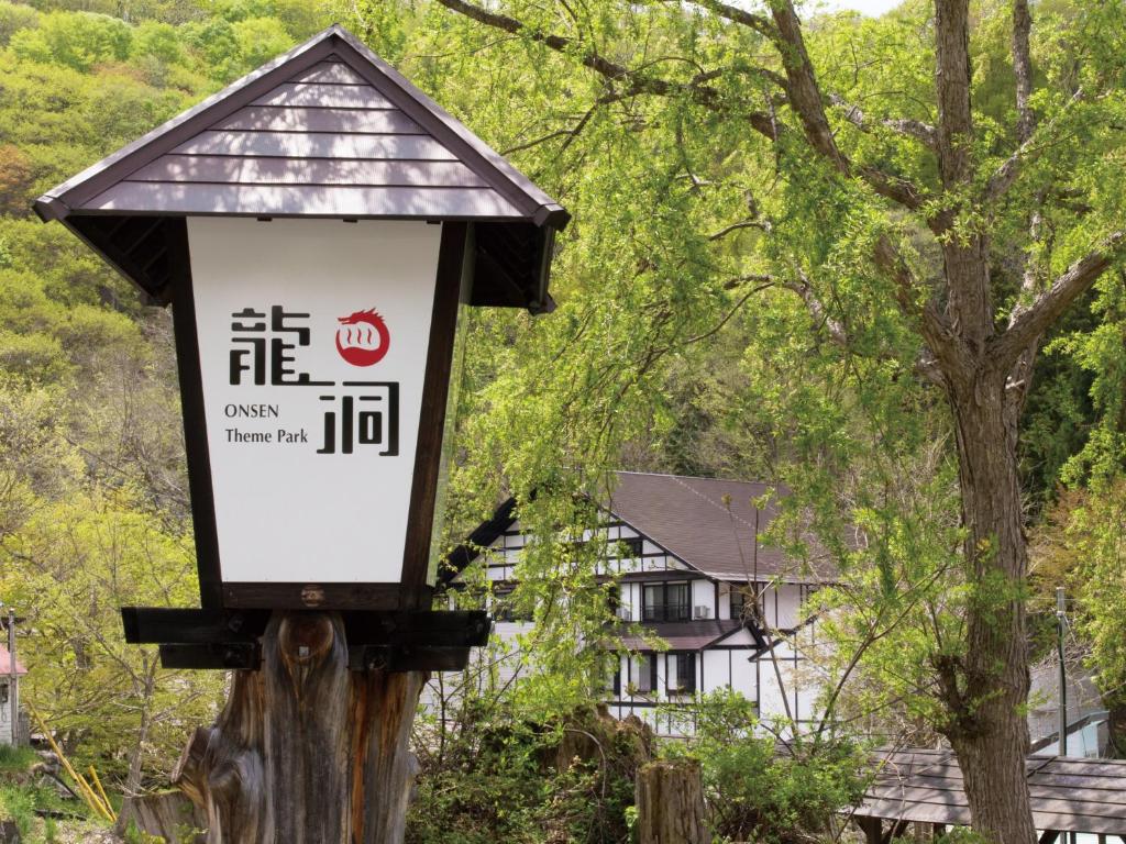 Lantern sign at Ryuudo Ryokan Gunma Wooden lantern sign with Japanese characters beside Ryuudo ryokan building amid verdant trees in Gunma