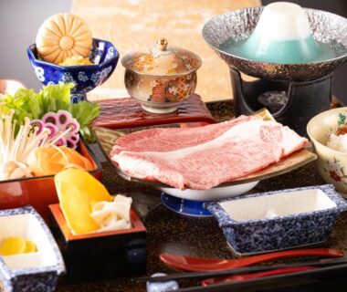 Tray of assorted Japanese dishes with marbled beef, pickles, rice bowl and simmering pot at ryokan table