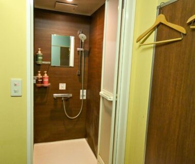 Compact wooden shower with wall-mounted fixtures at SDGs BASE AQUA PLUS, Chūbu, Ishikawa, Japan