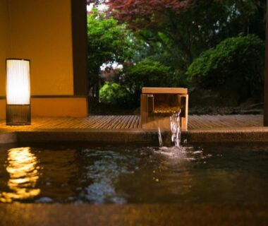 Indoor wooden onsen bath with flowing spout and garden view at SEKIYA RESORT Bettei Haruki, Ōita, Kyūshū
