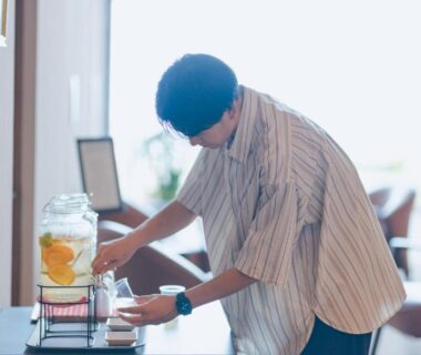 Guest in yukata pouring citrus water from dispenser in ryokan lounge at SEKIYA RESORT, Ōita